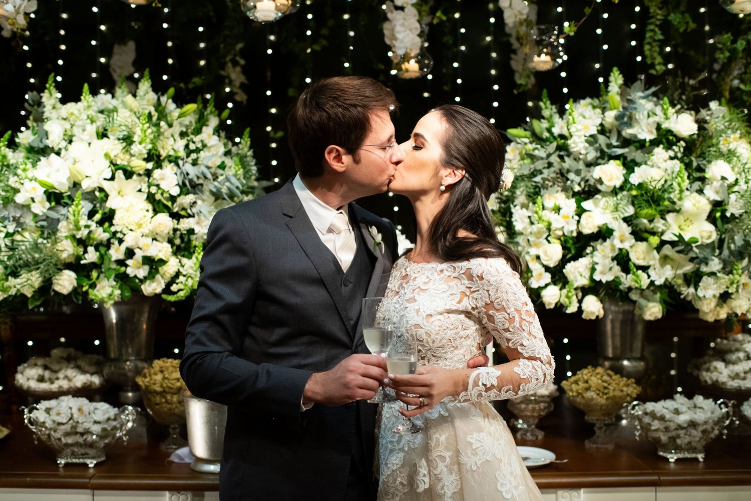 Elegant wedding reception venue decorated with hanging lights and white floral arrangements.
