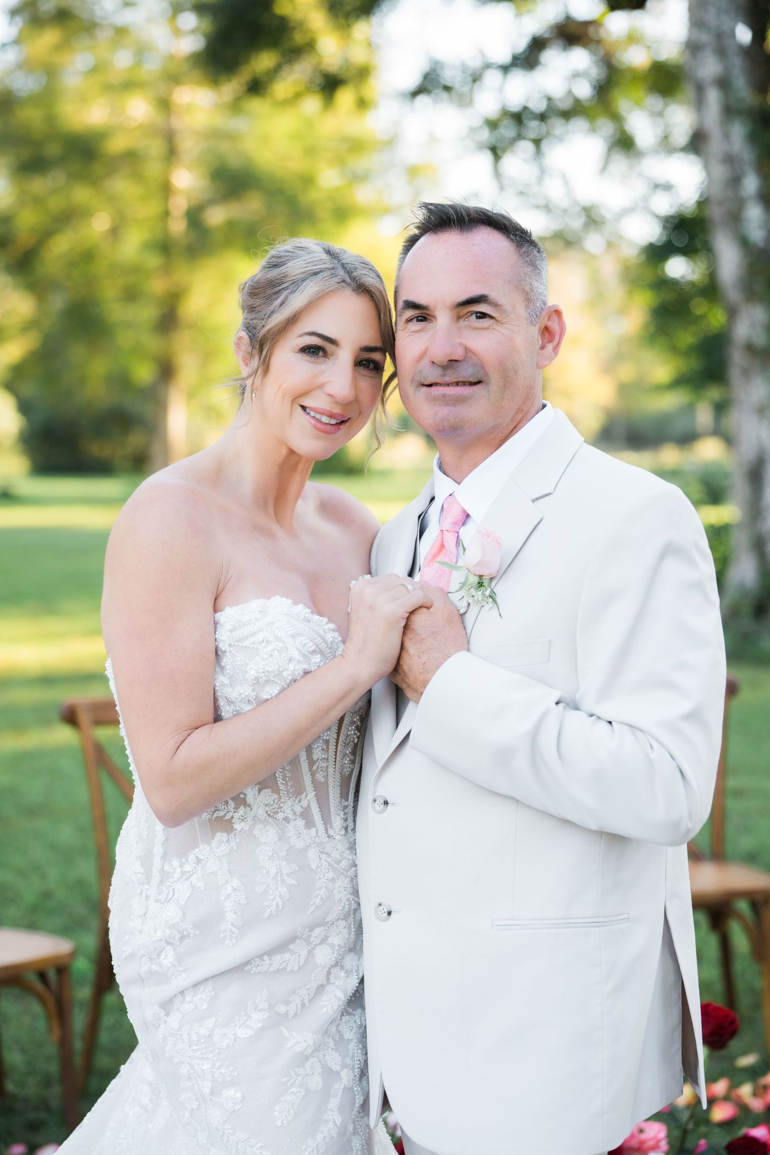 Wedding couple in white attire embrace during outdoor photo session.