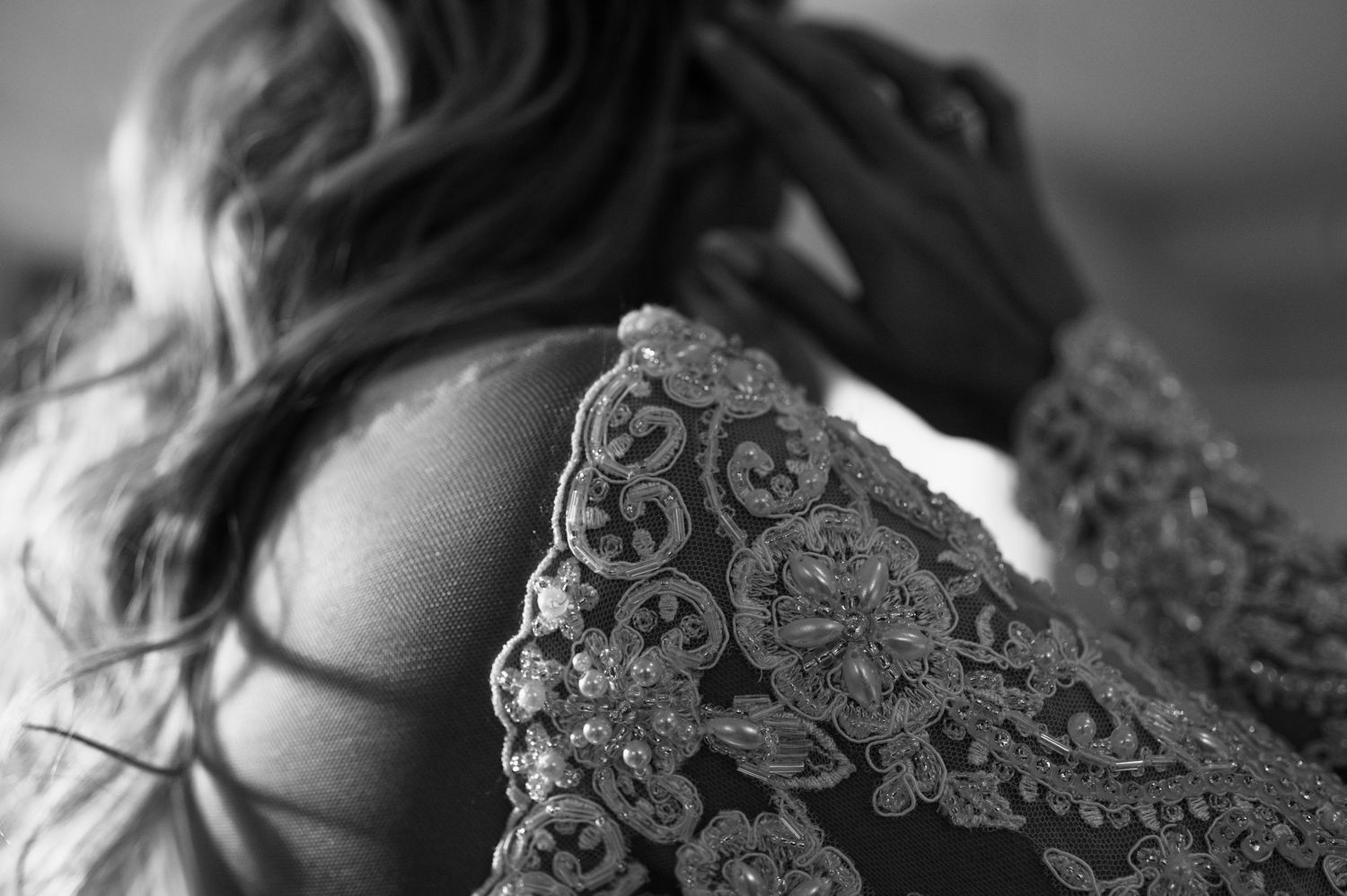 Delicate lace detail of wedding dress captured in black and white close-up.