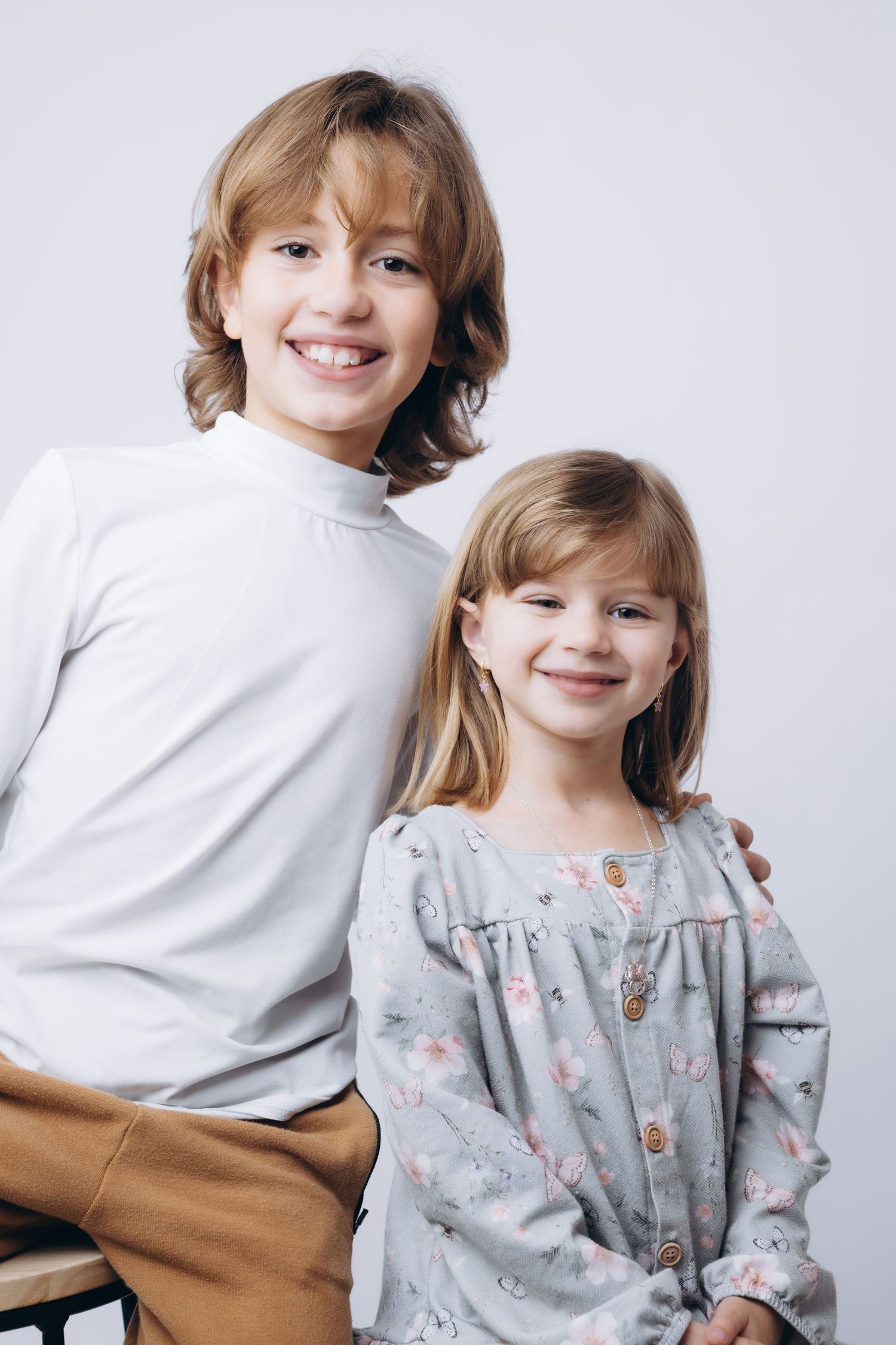 Studio portraits of children in white and gray floral outfits showing playful expressions.