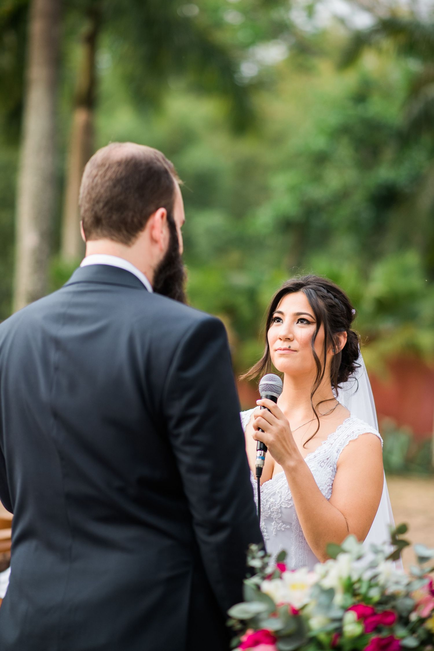 A couple shares an emotional moment during their wedding ceremony with colorful floral arrangements in the background.