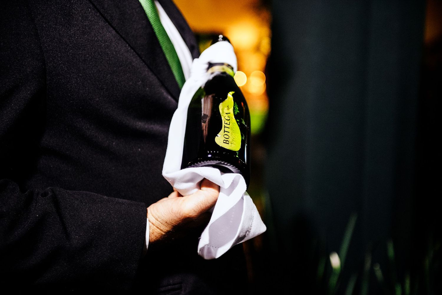 Close-up detail of formal attire with white pocket square against dark background.