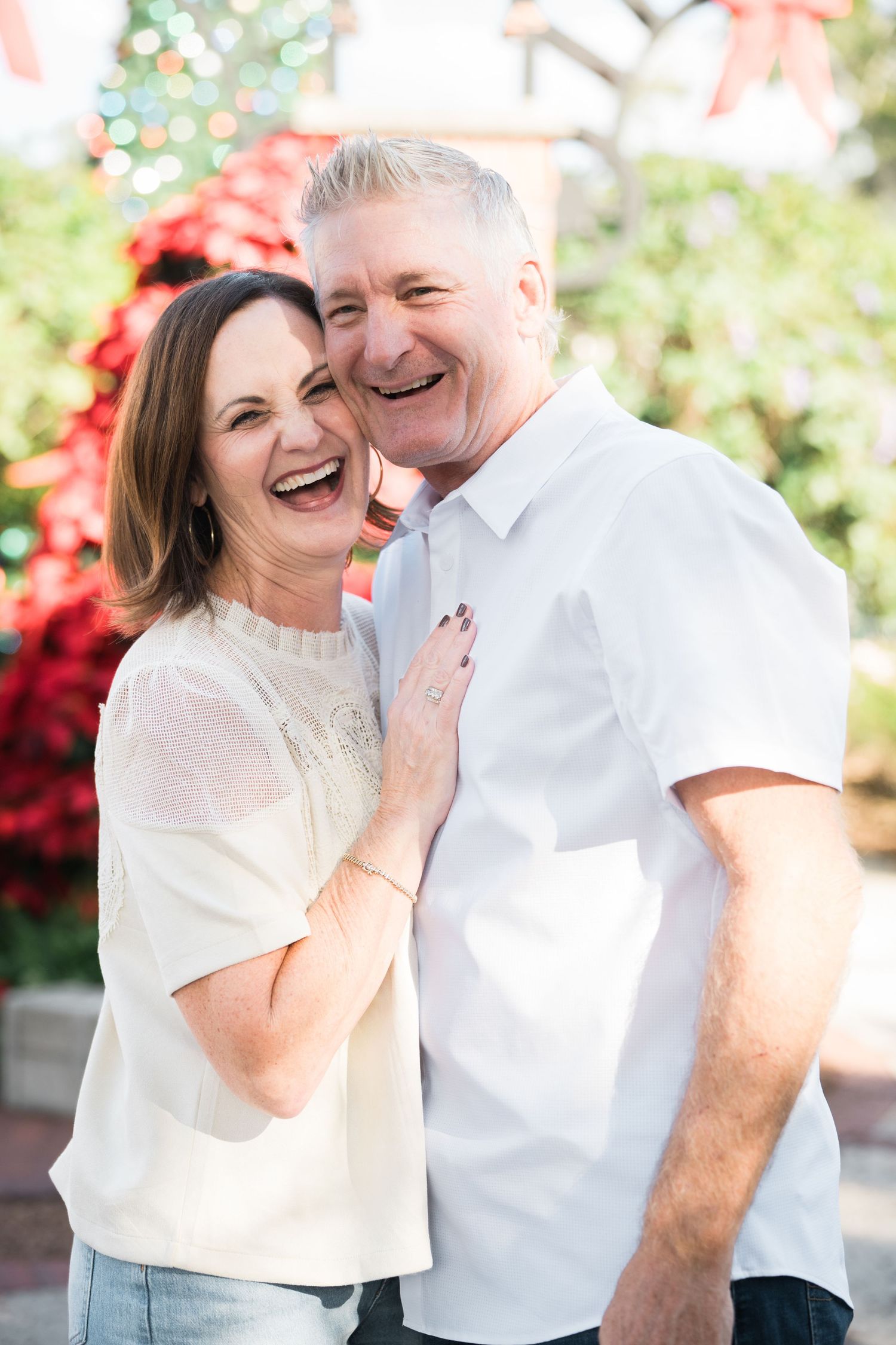 A joyful outdoor photoshoot features people in white tops sharing genuine laughter.