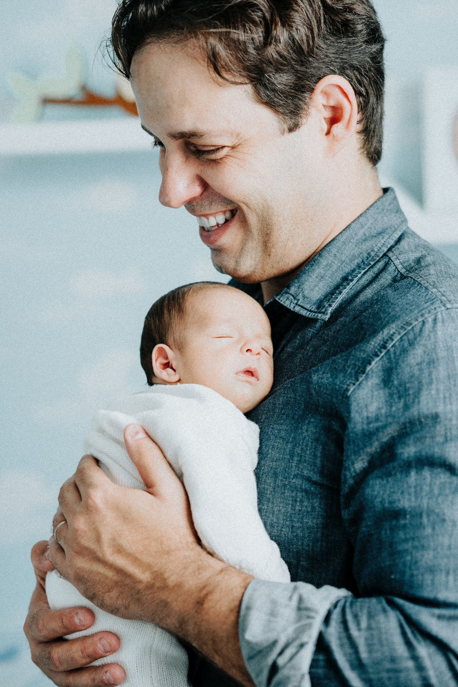 Parent in denim shirt holds and smiles at their newborn baby in progressive sequence of photos.