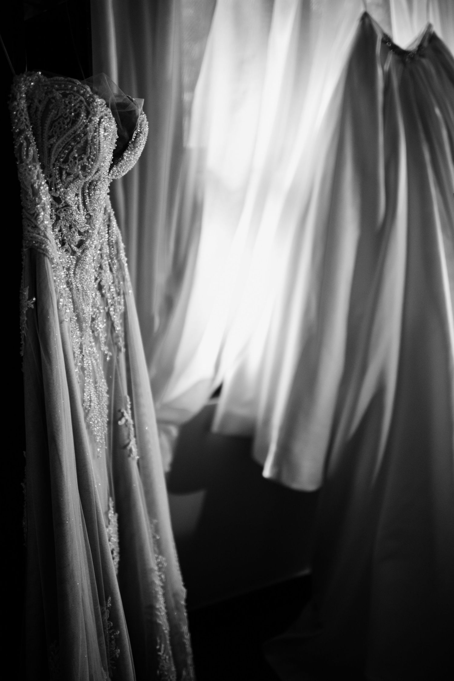 Close-up details of a white lace wedding dress against soft window light.