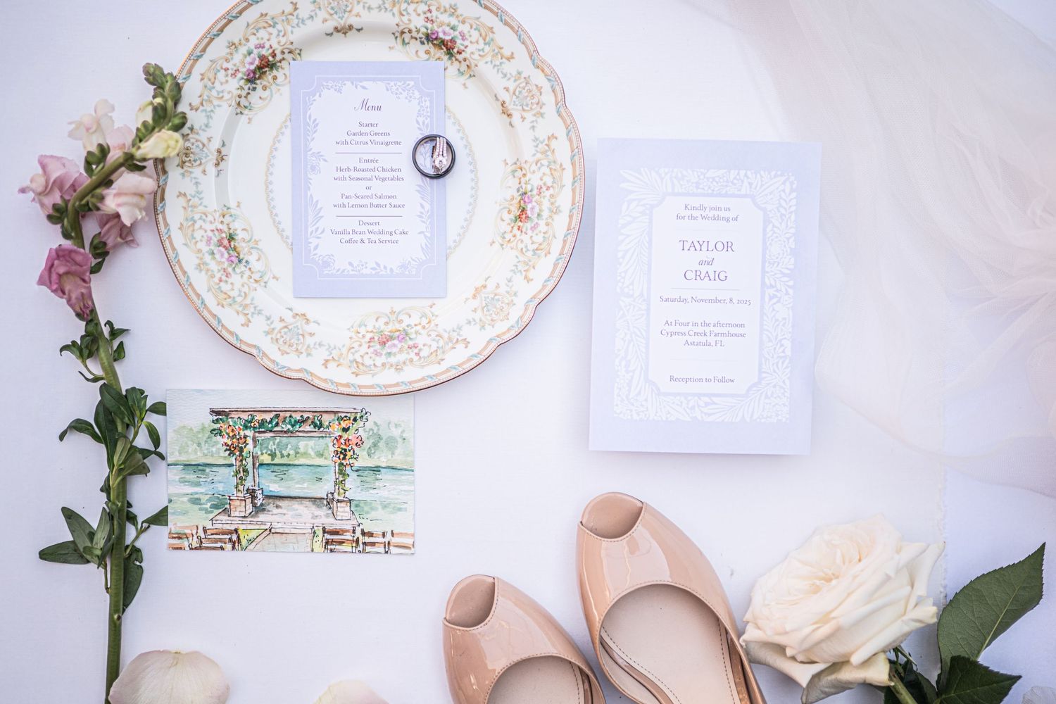 Vintage decorative plates and wedding details arranged on a white surface with floral accents.