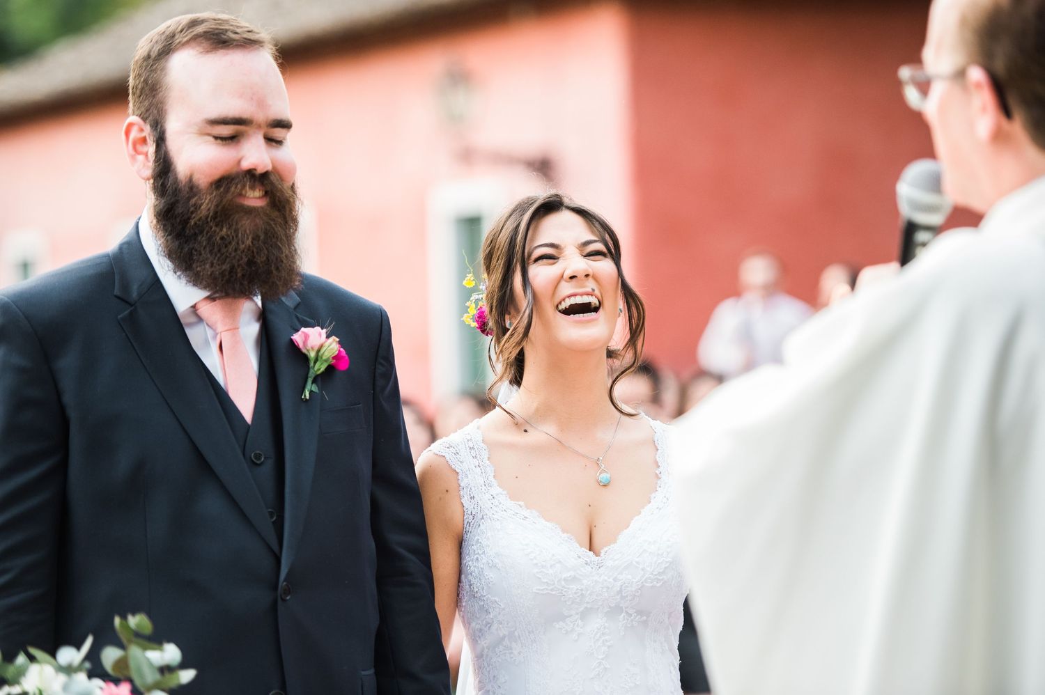 A romantic wedding couple shares intimate moments in a coral-colored setting.