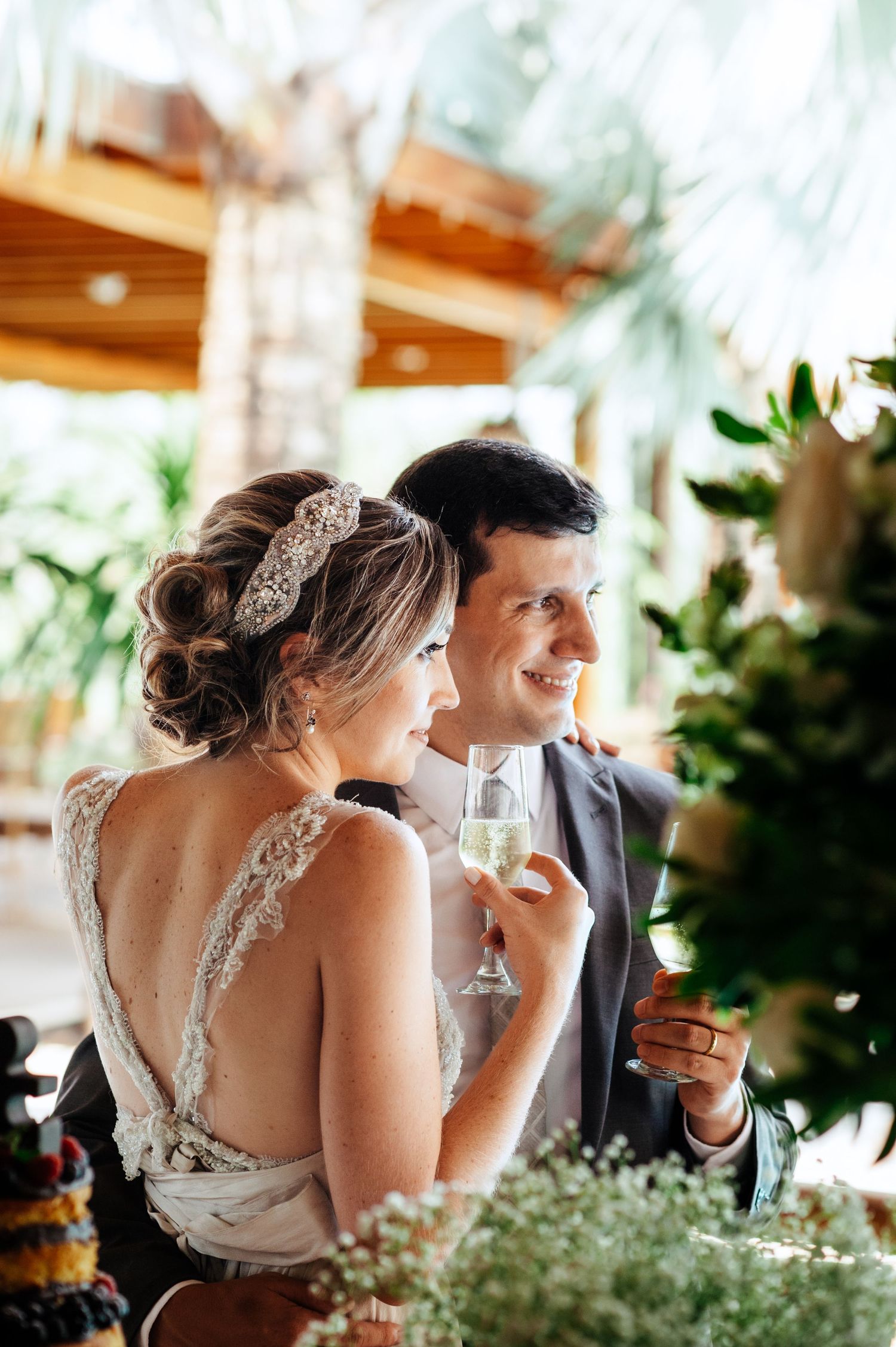 Wedding couple sharing drinks at a rustic reception venue with natural decor.