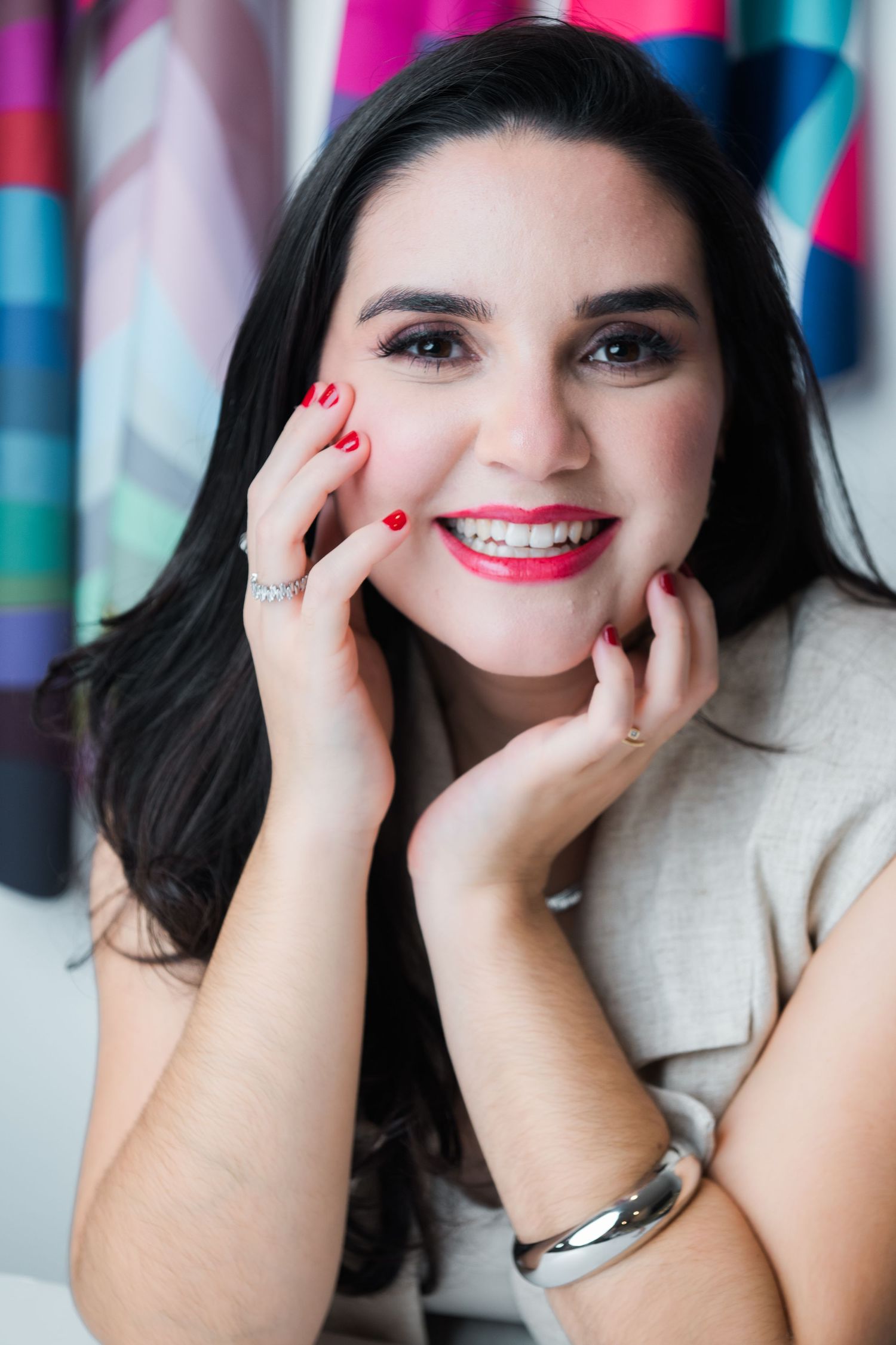 A series of four close-up photos showing a bright smile with red nail polish and dark hair against a colorful background.
