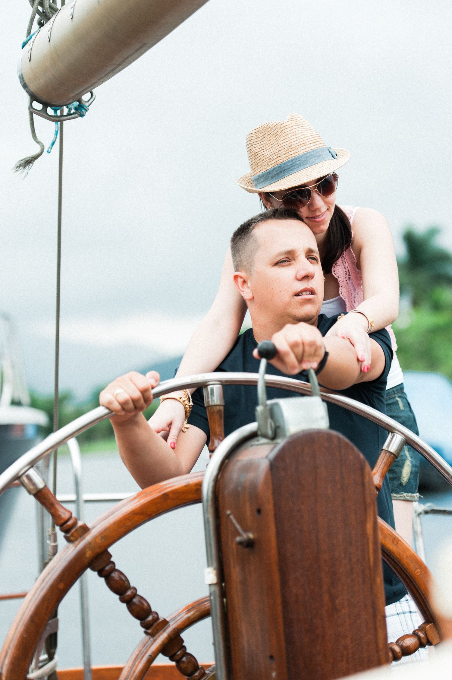 Couple enjoying romantic moment at ship's wheel on sunny day.