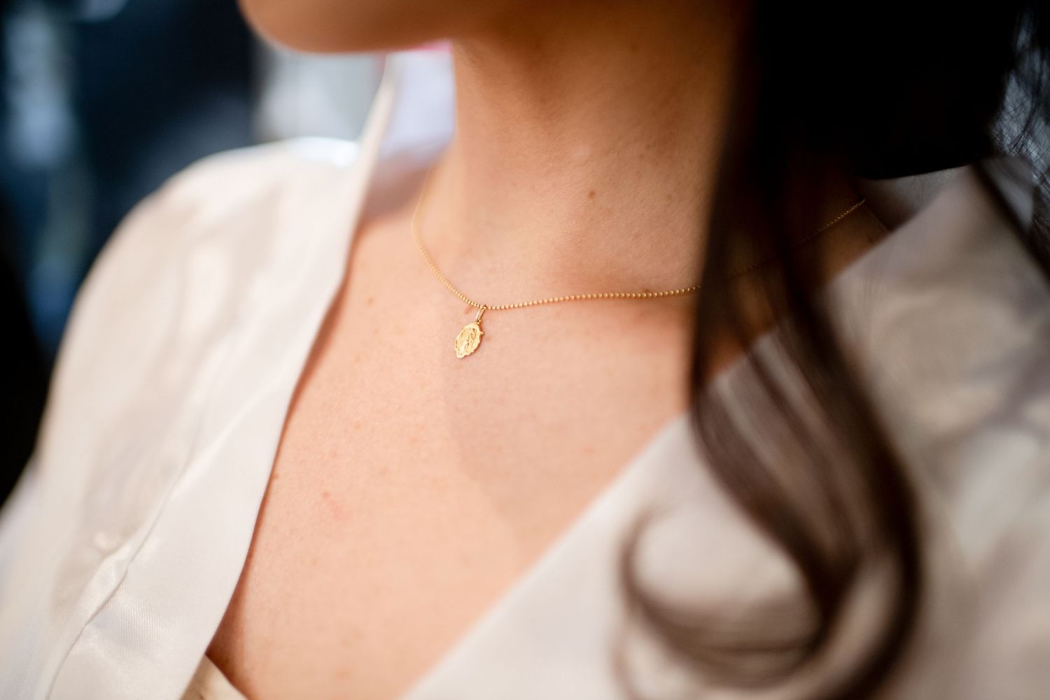 Delicate gold initial necklace worn by someone in a white robe.
