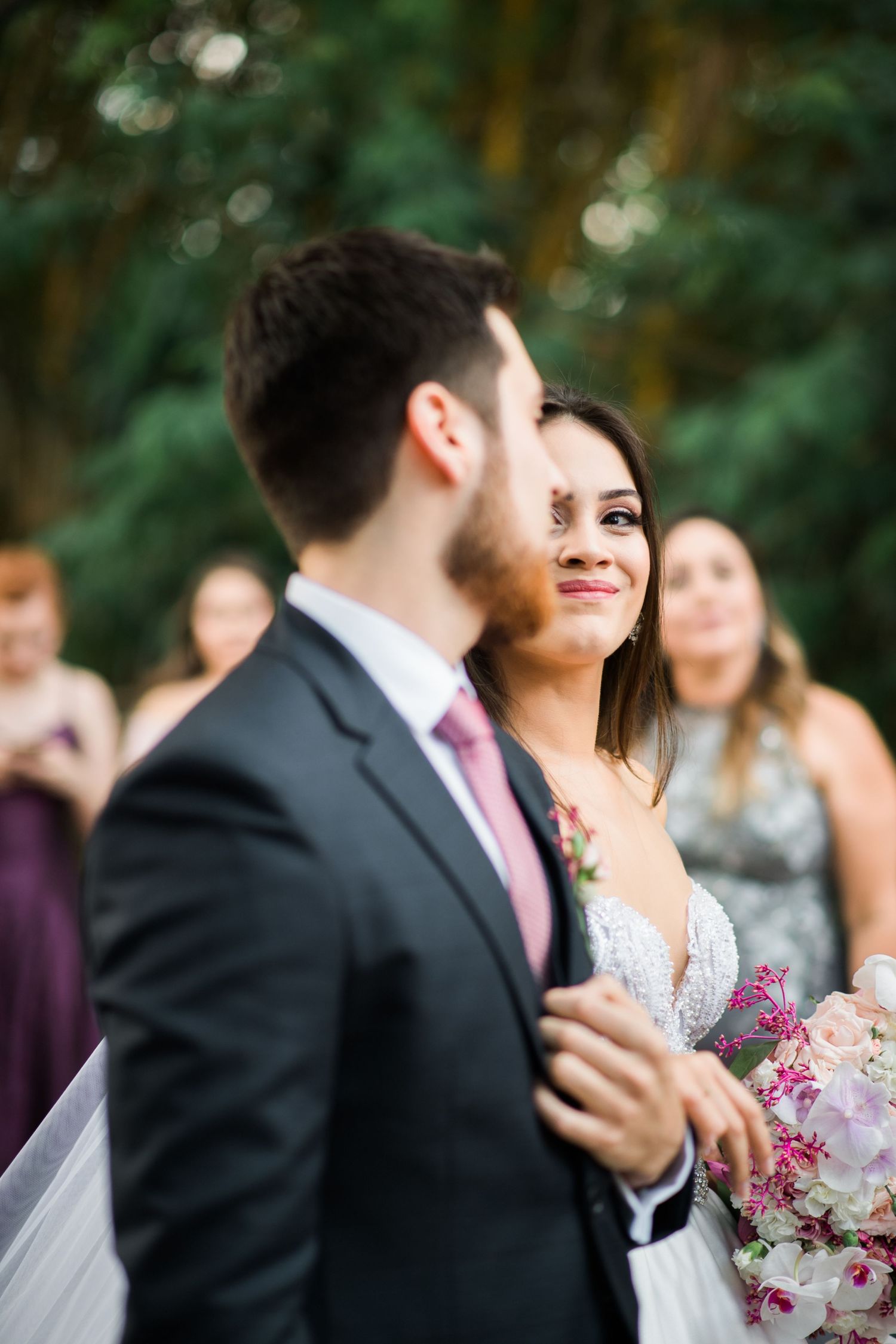 Candid moments captured during an outdoor wedding ceremony with pink floral accents.