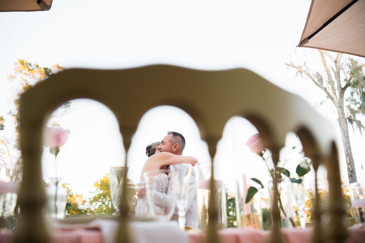 Elegant outdoor wedding reception tables arranged with umbrellas and decorative settings.