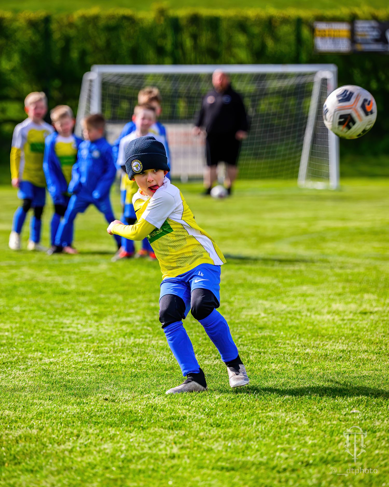 Young football player in yellow and blue uniform prepares to throw the ball into play.