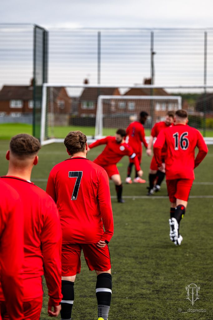 Soccer players in red jerseys warm up on a green field with jersey numbers 7 and 16 visible.