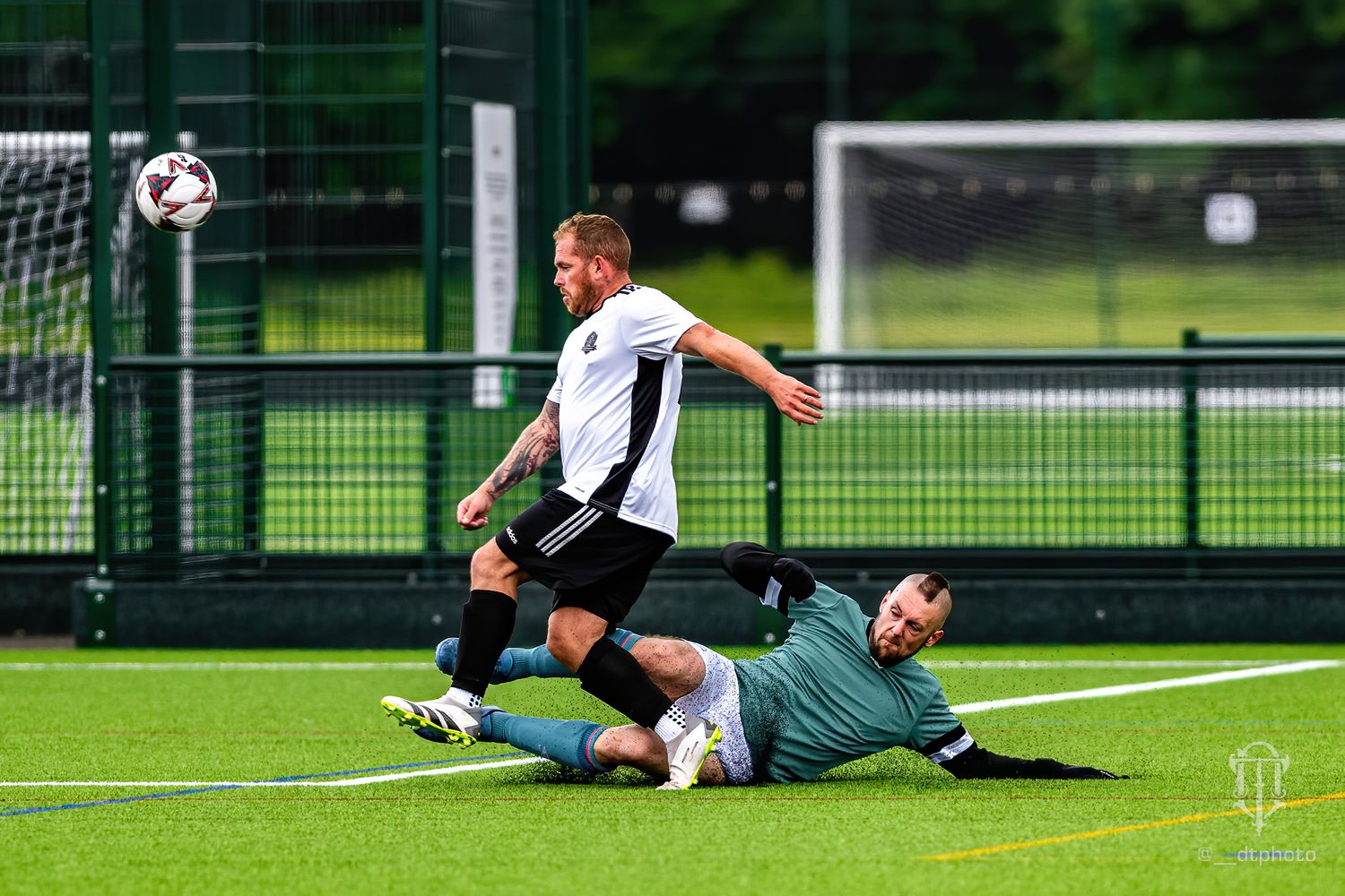Football match showing a footballer making a tackle for the ball.