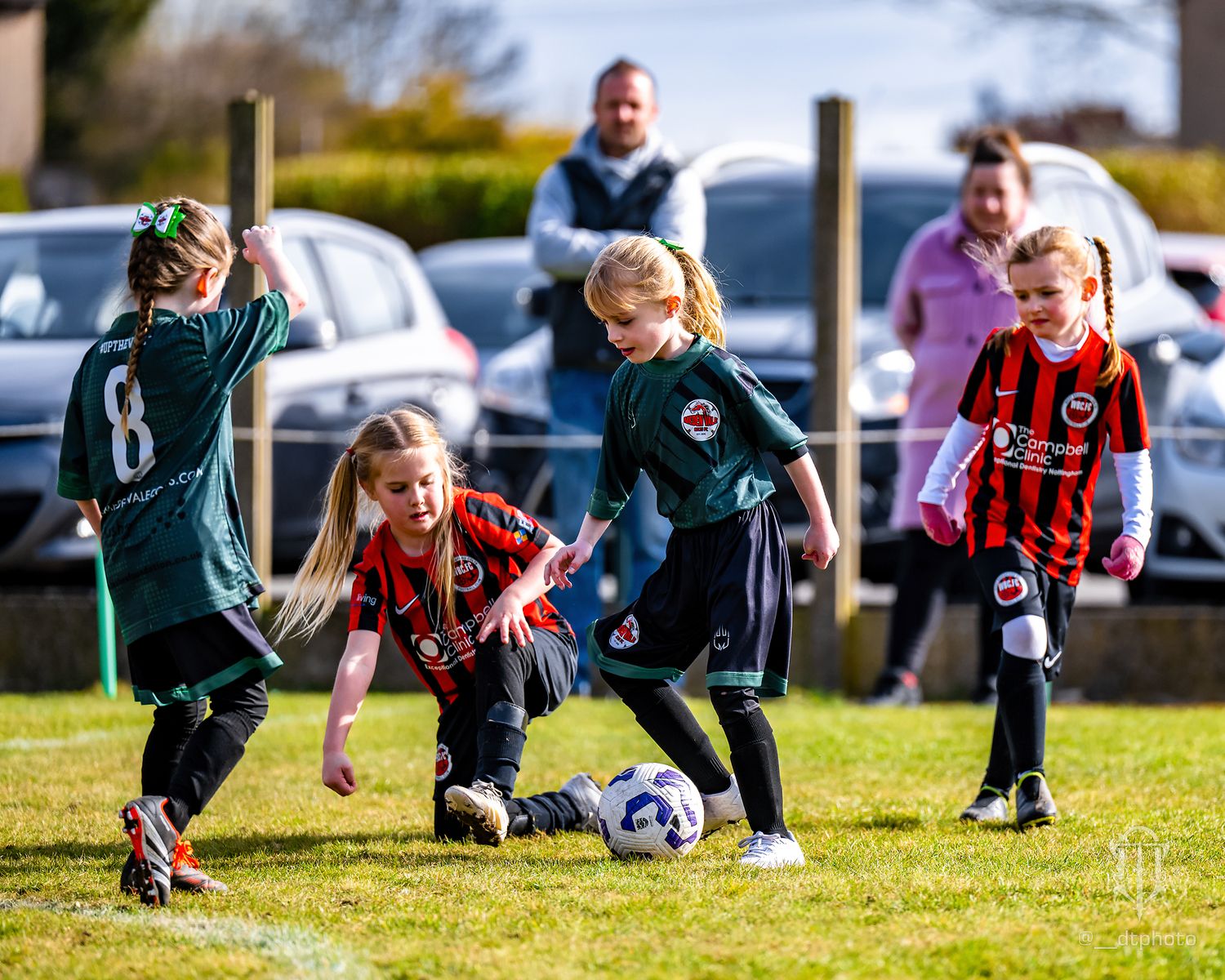 Youth football players from opposing teams battle for control of the ball during a match.
