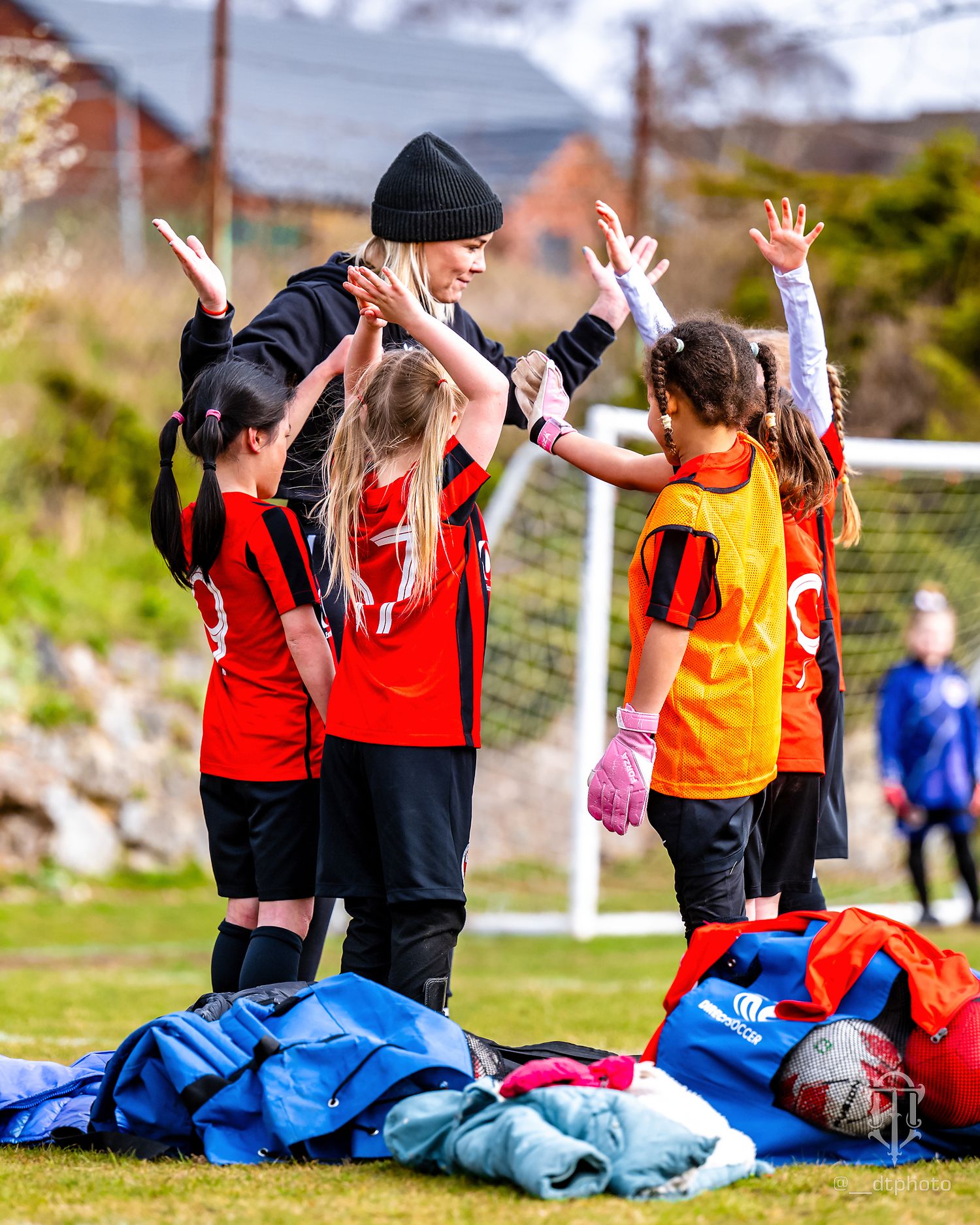 Football coach celebrates with enthusiastic young players on the field.