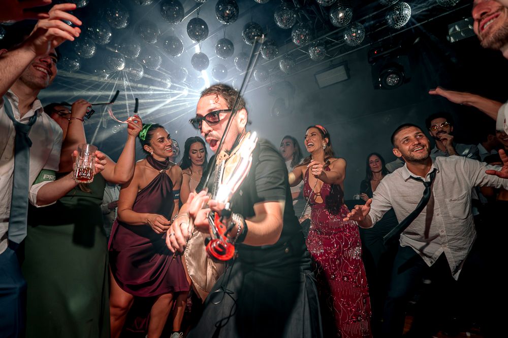 People dancing and celebrating at a lively party or reception with dark atmospheric lighting. wedding in mendoza