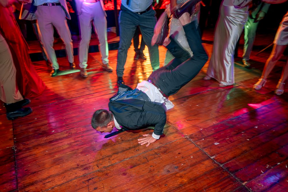 People dancing on a wooden dance floor illuminated by red and purple lighting at a lively party or club event. wedding in mendoza