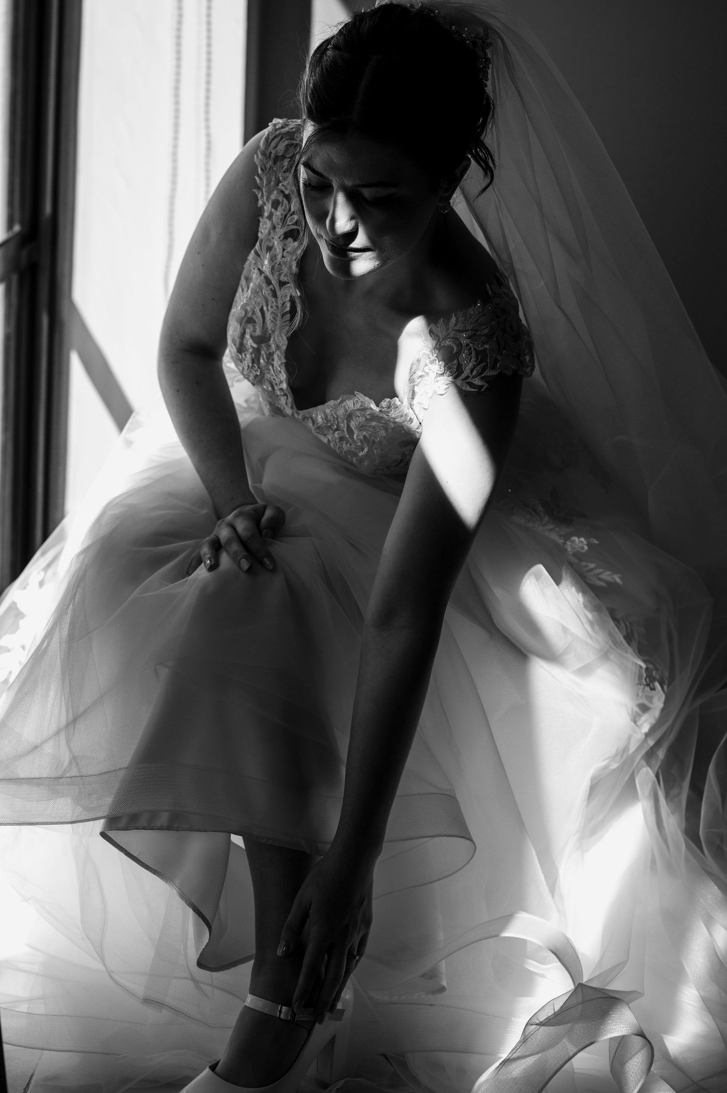 Black and white artistic sequence showing bride in lace wedding dress preparing with ethereal window lighting.