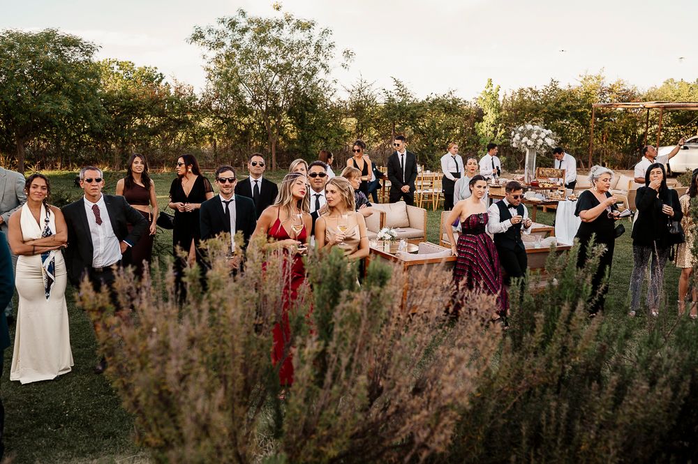 A large group of wedding guests gather outdoors in a garden with lavender plants during a golden hour celebration. wedding in mendoza