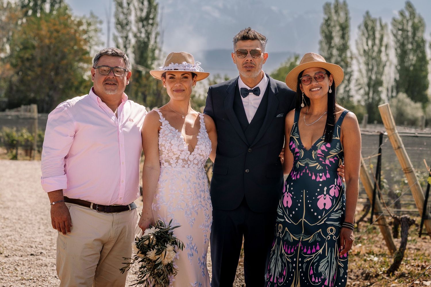 Family members pose together at an outdoor event with tall poplar trees in the background.