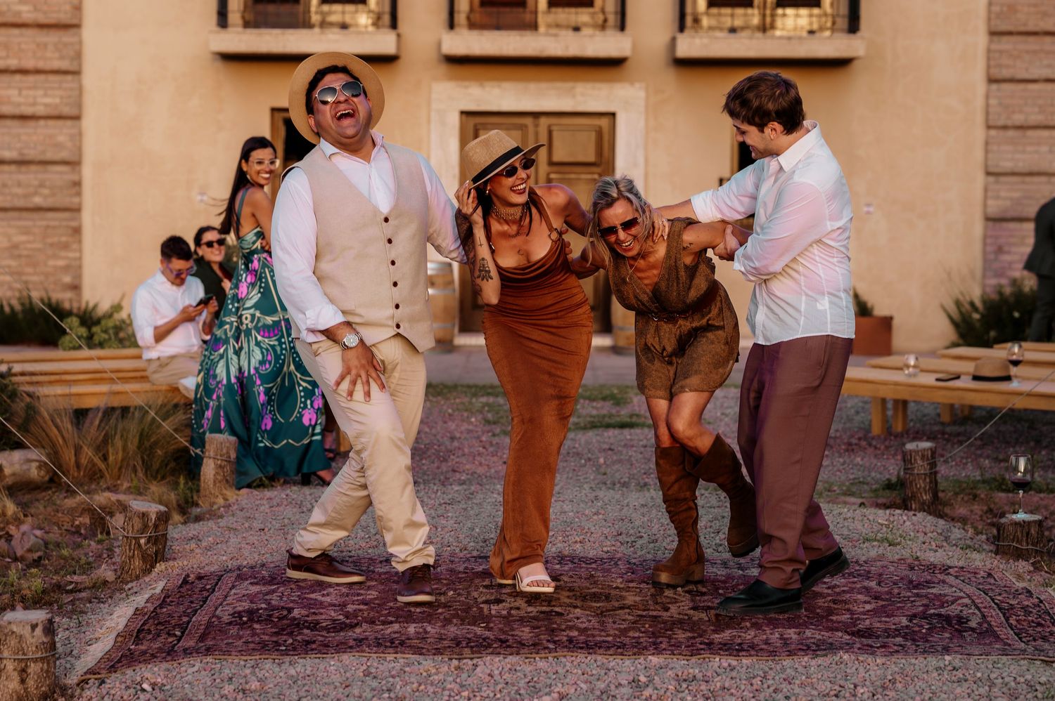 People stomping grapes in a traditional winemaking process on a purple-stained mat outdoors.