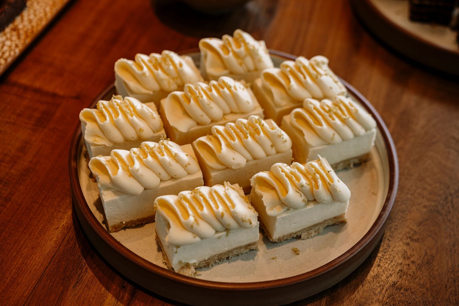 A series of six identical rectangular desserts with white cream topping and caramel drizzle arranged on white plates.