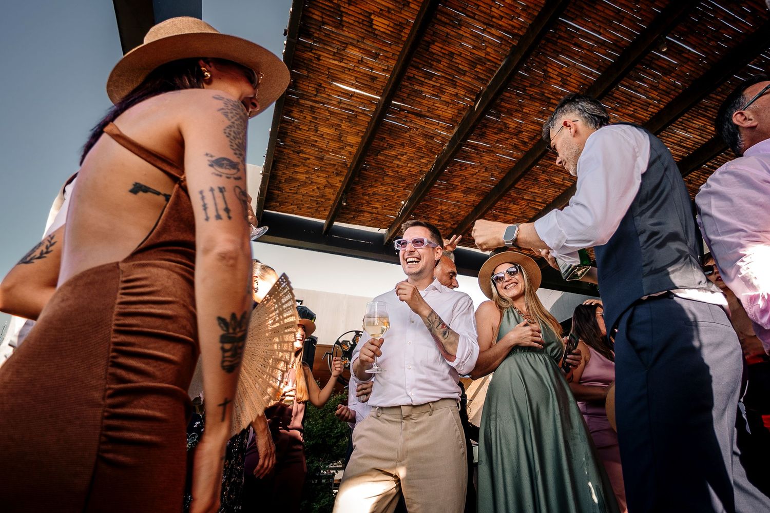 Wedding guests dancing and celebrating on a rustic wooden dance floor during an evening reception.