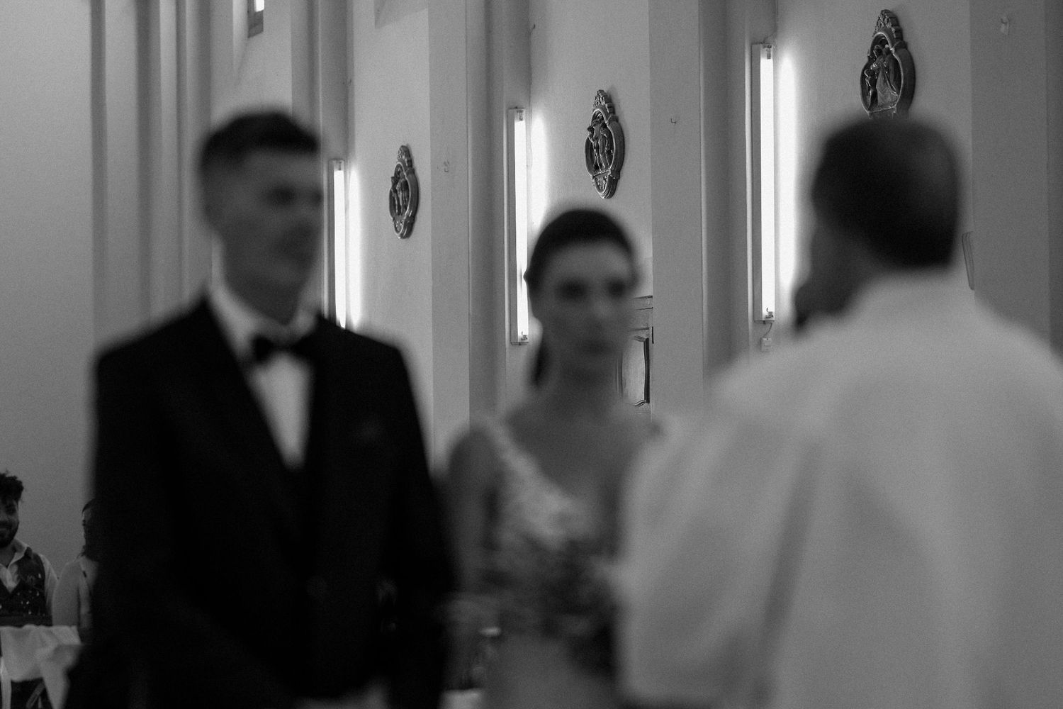 Black and white photograph of a church ceremony aisle with guests seated on both sides.