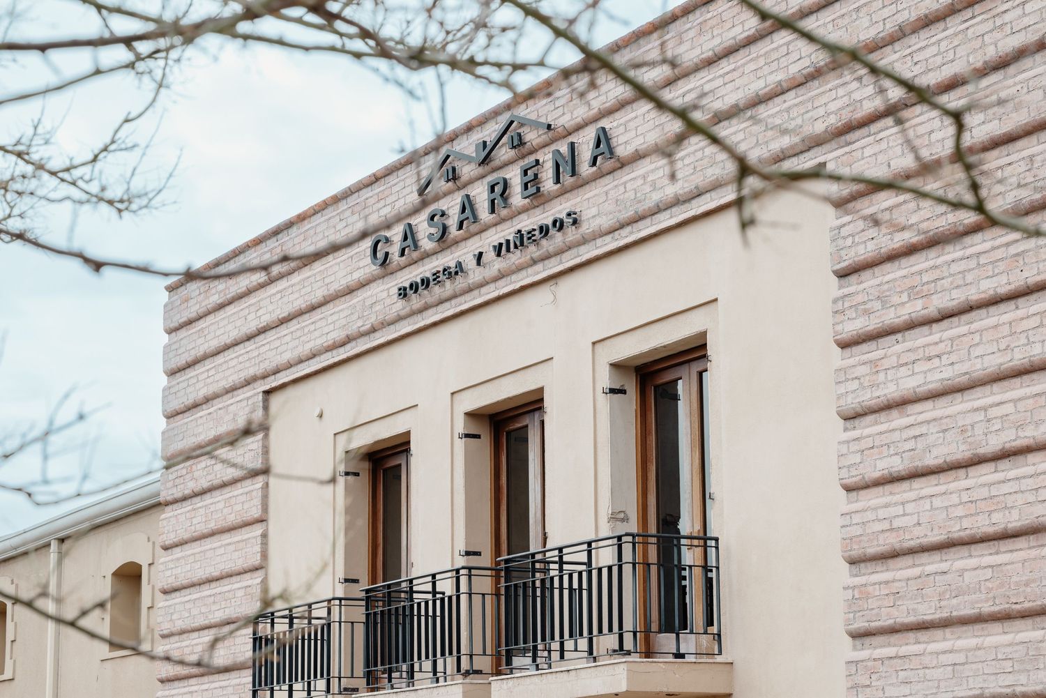 A vintage building facade with 'Tasarama' signage and three windows with black iron balconies against striped stone walls.