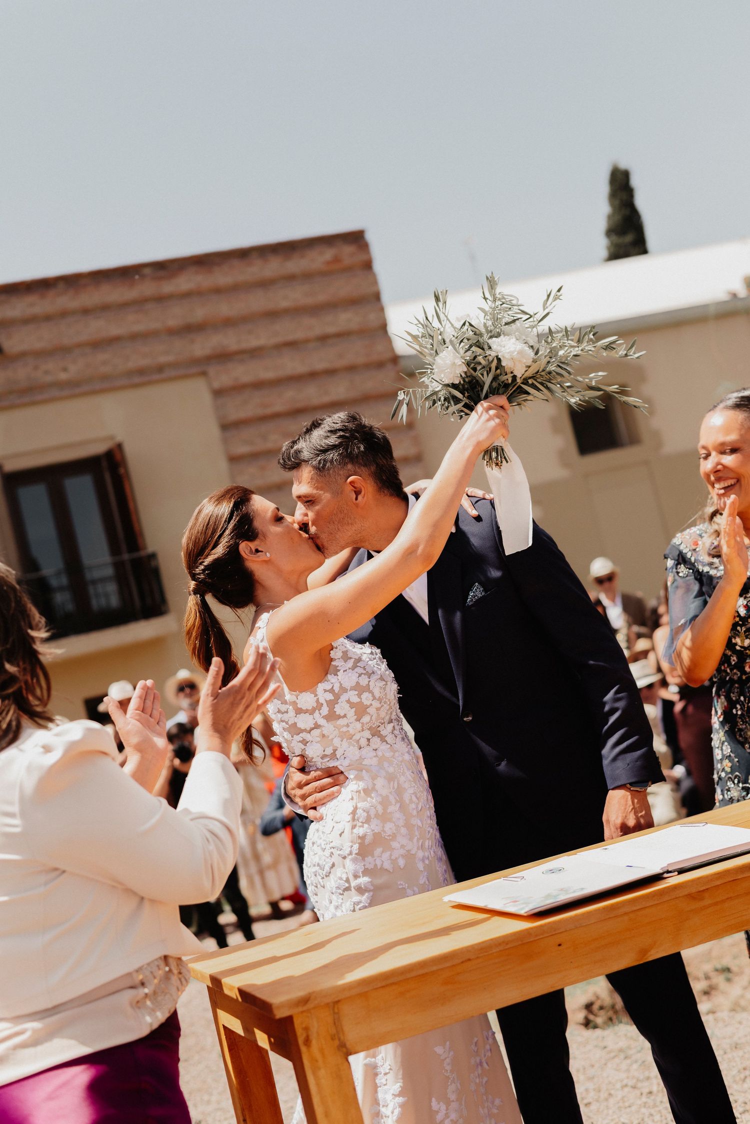 Couple shares a joyful dance moment during their wedding reception on a sunny outdoor patio.