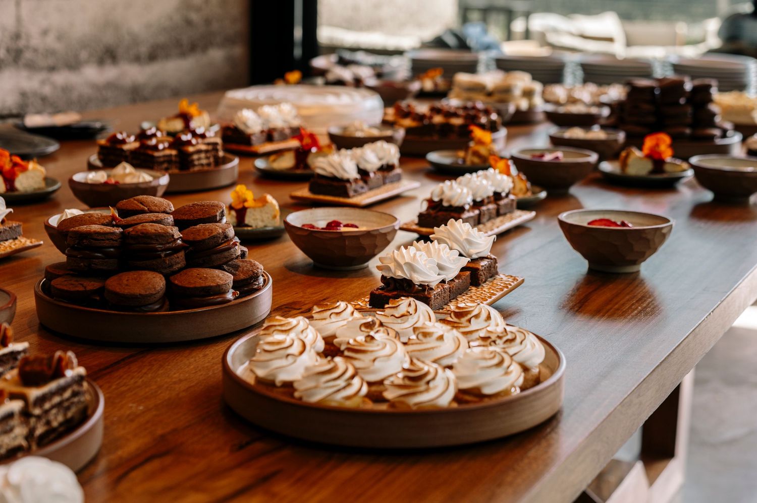 Assorted chocolate desserts and pastries displayed on wooden boards at an elegant dessert table setup.