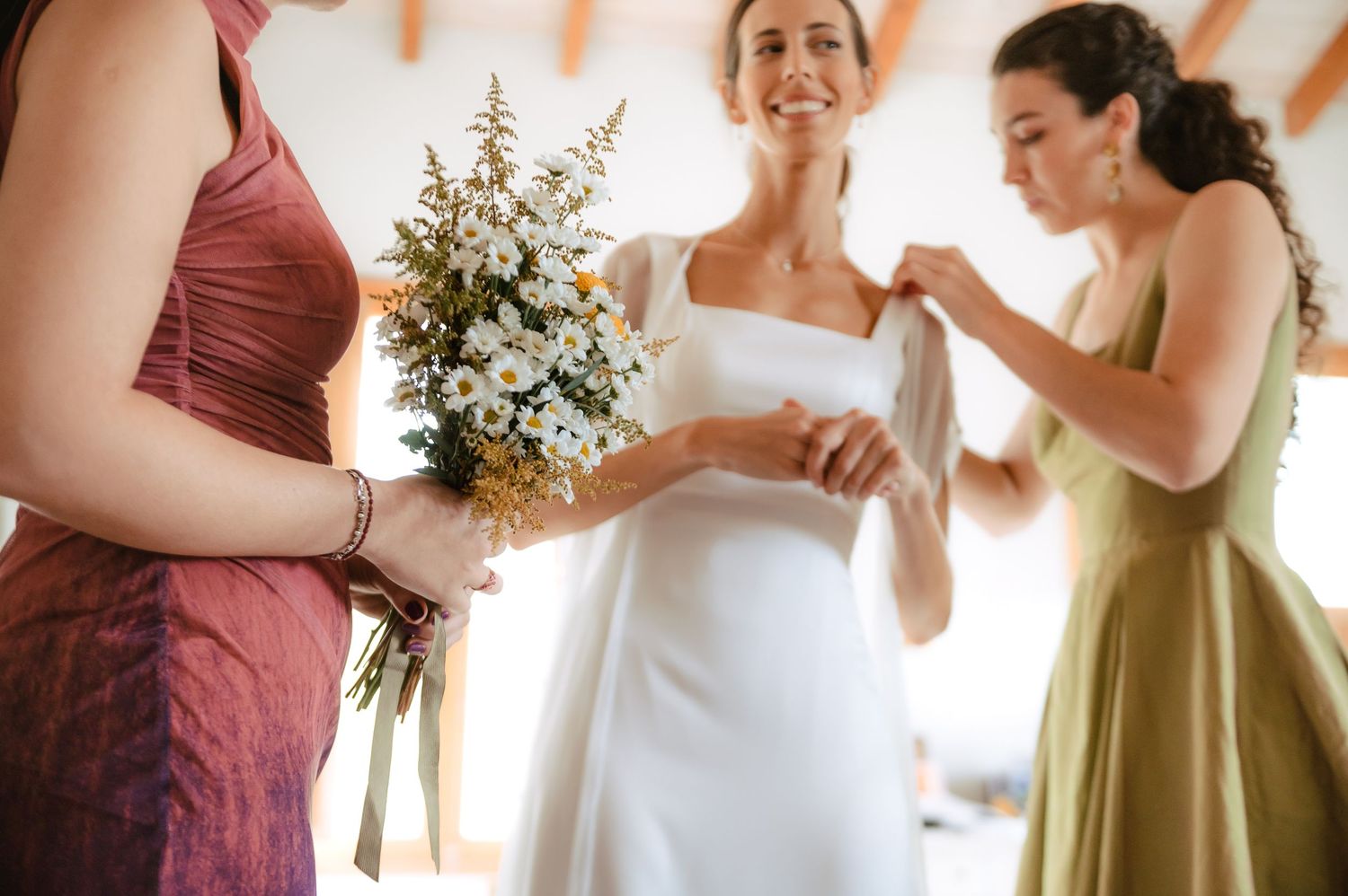 Wedding party members in burgundy and white attire dancing in a celebratory line at an outdoor reception.