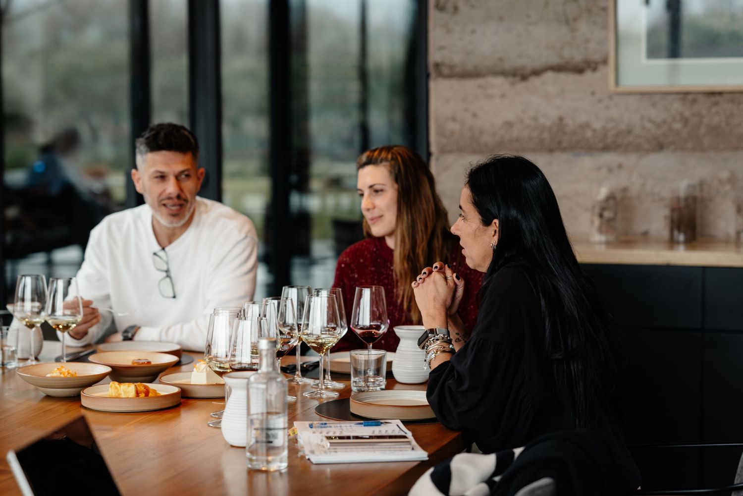 A group of people dining together at a restaurant with wine glasses and dishes on the table.
