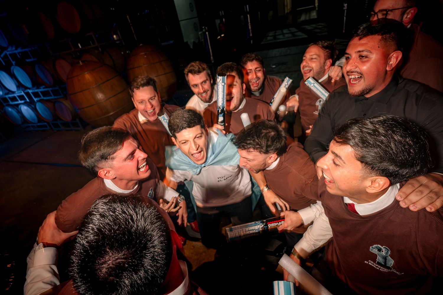 Group of men celebrating together in a dimly lit venue, smiling and posing for a photo.