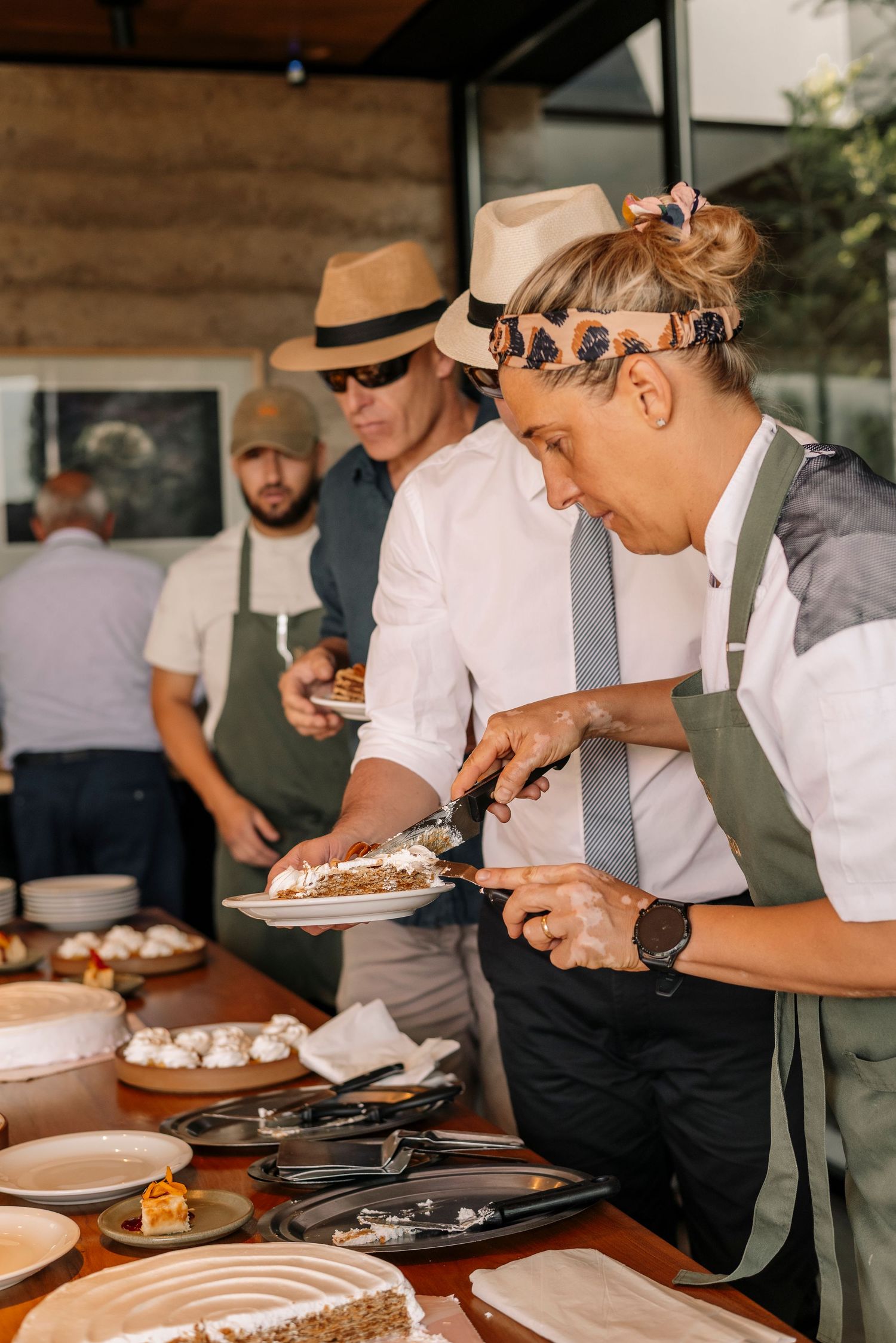 Catering staff in white uniforms carefully plate dishes at an upscale event.