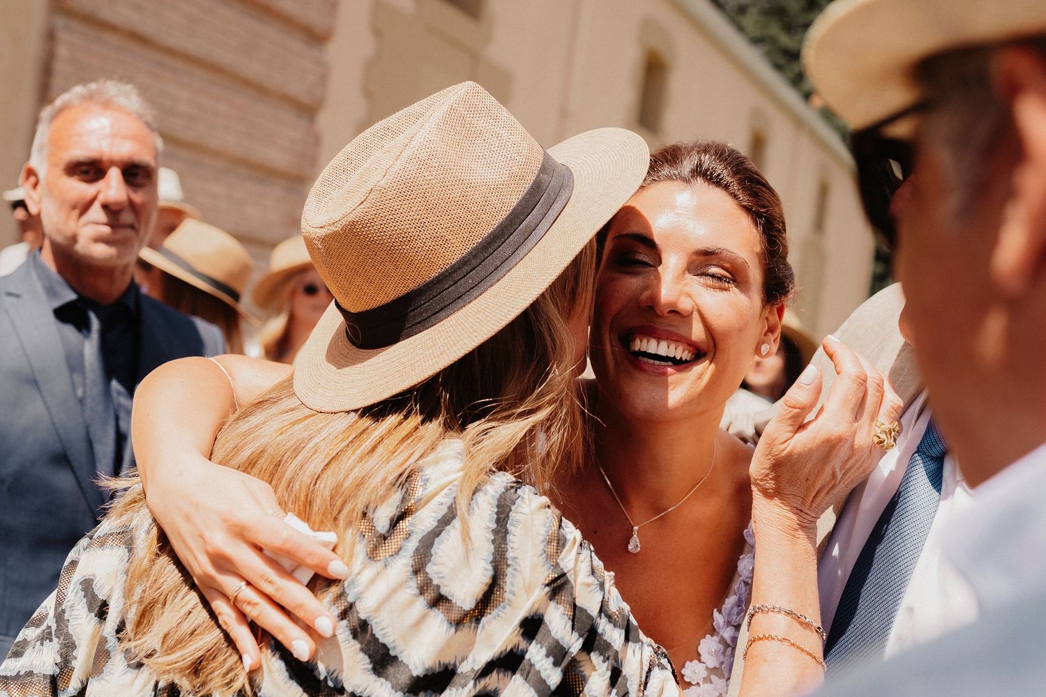 A group of people in summer attire celebrating outdoors with drinks and laughter at a social gathering.