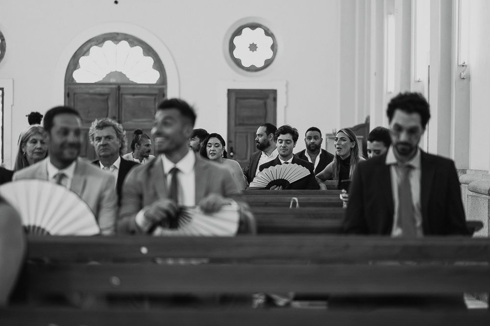 A black and white photograph showing people seated in wooden pews inside a church or courtroom setting. wedding in mendoza