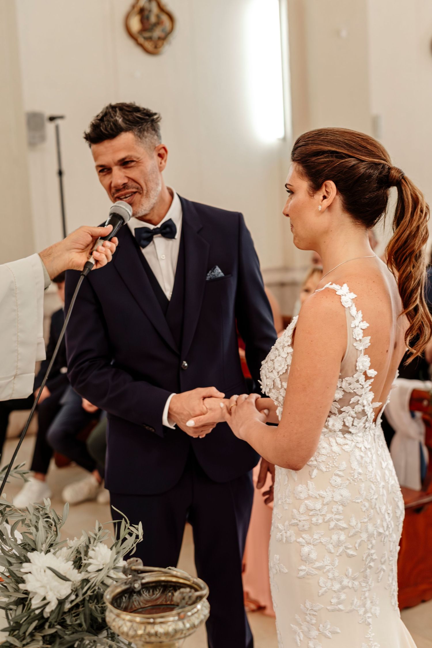 A couple shares an emotional moment during their first dance at an elegant indoor wedding reception.