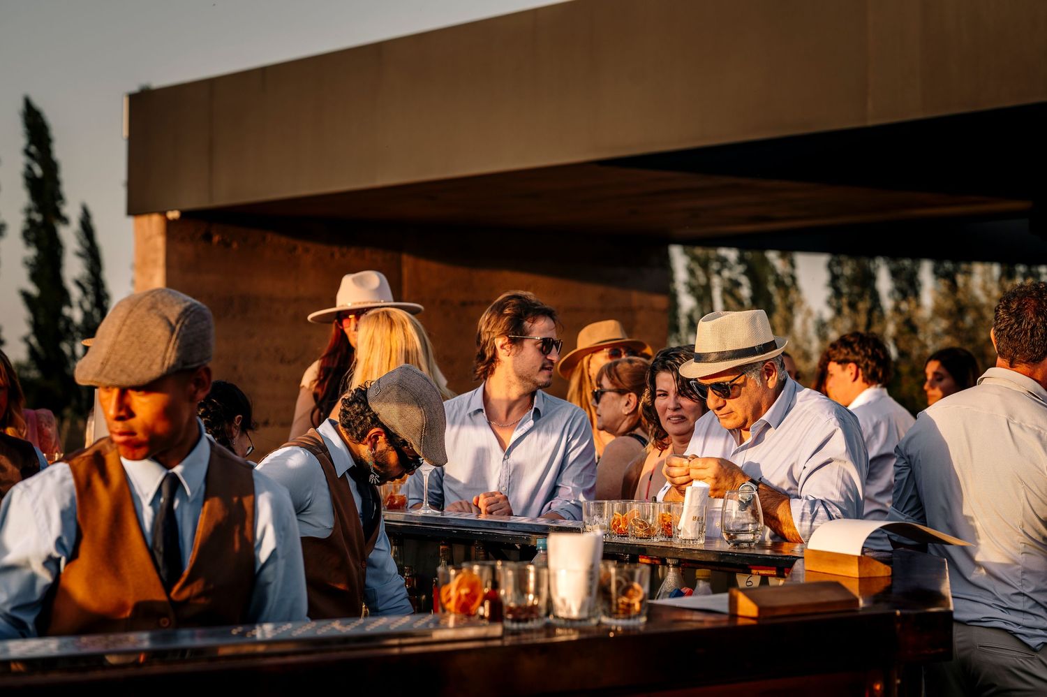 People gather at an outdoor restaurant bar during sunset, creating a warm and inviting social atmosphere.