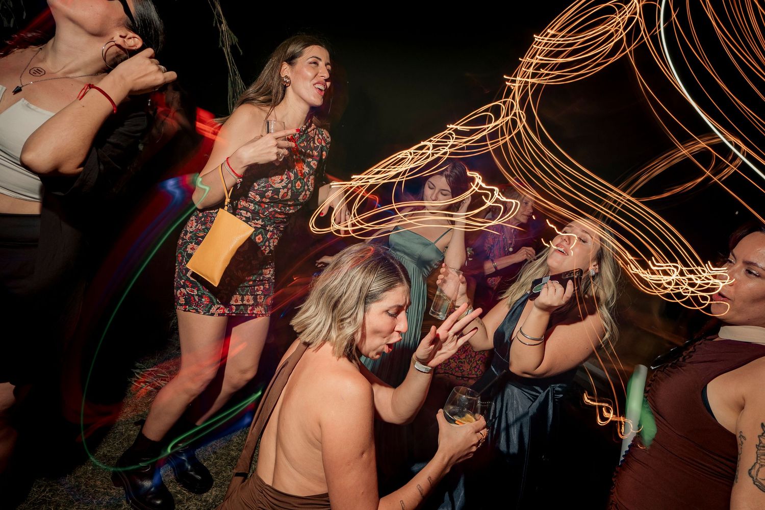 A group dances together at a nightclub with colorful lighting and motion blur effects creating a dynamic party atmosphere.