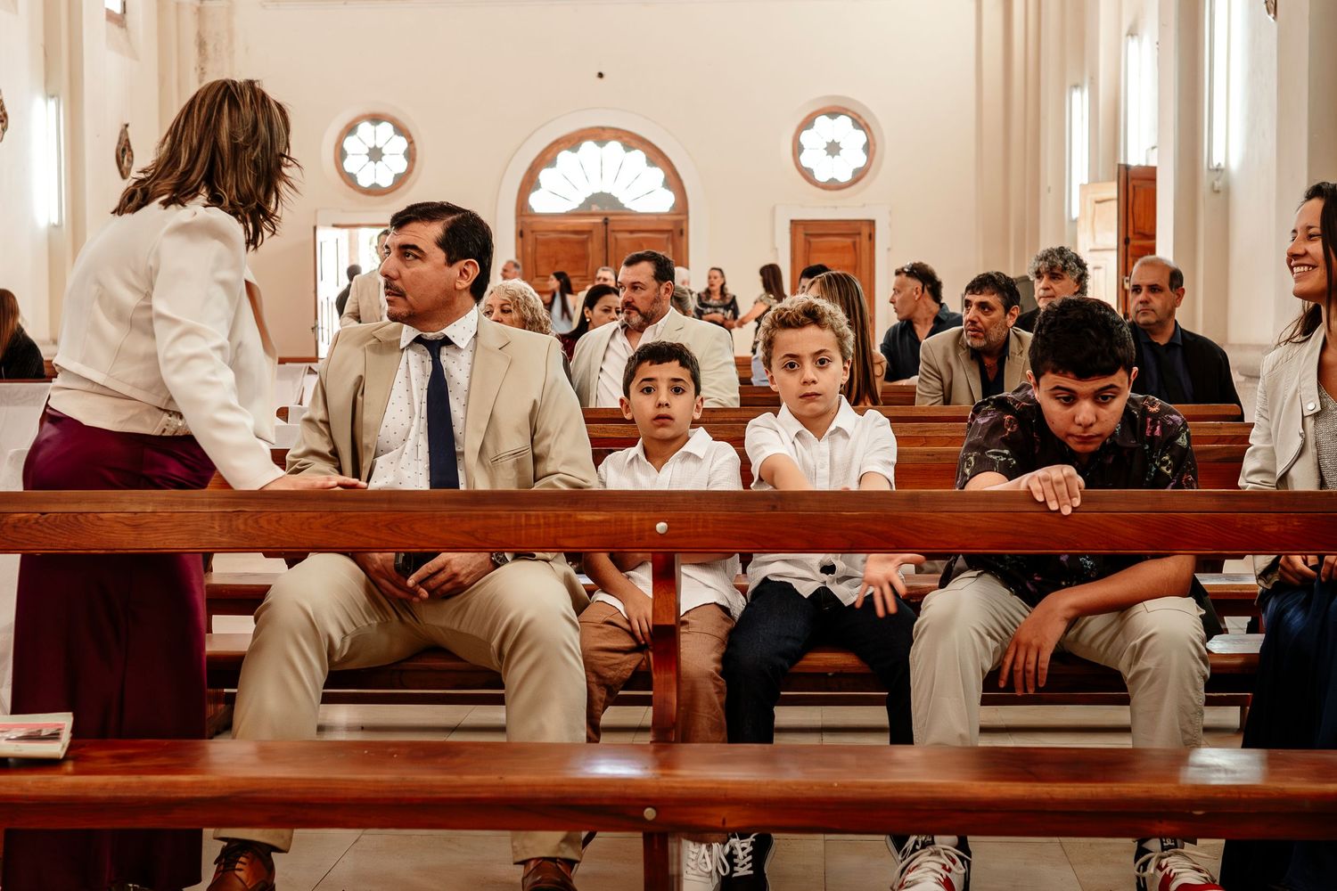 A group of people sit in wooden pews during a church service or religious gathering.