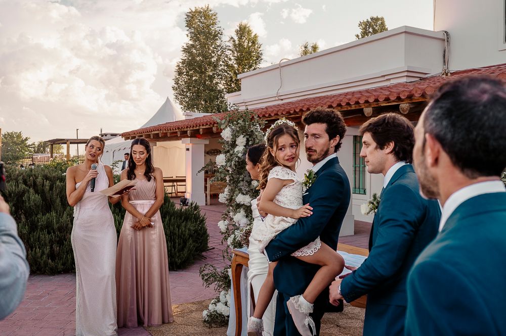 Wedding party celebrates joyfully during outdoor reception with string lights overhead and sunset glow in background. wedding in mendoza