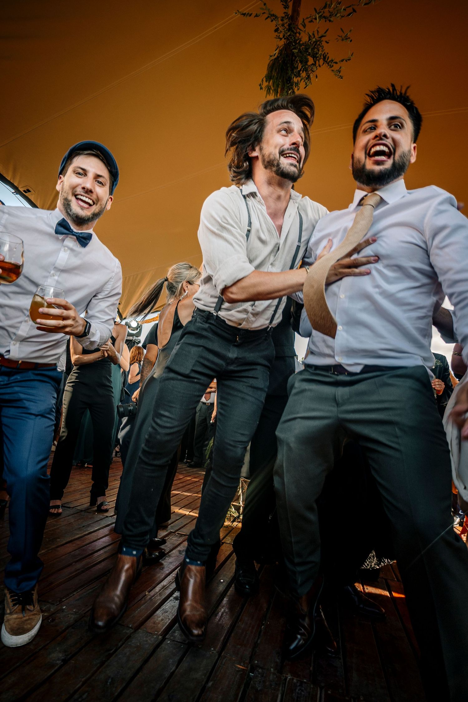 A sequence of candid party photos showing people in white shirts and dark pants laughing and dancing together.