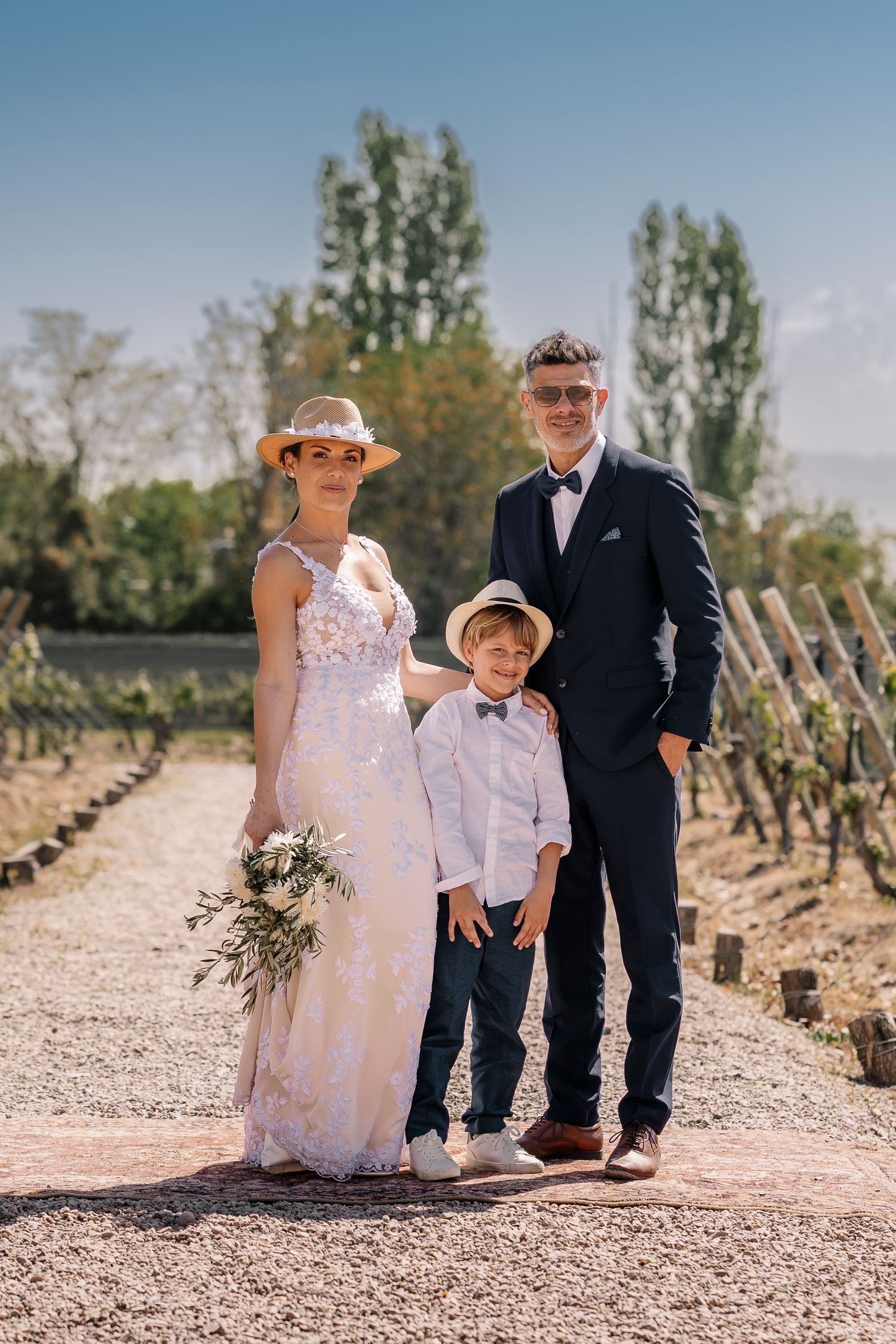 Wedding party members walk along a desert path surrounded by desert plants and cacti in a rustic outdoor setting.