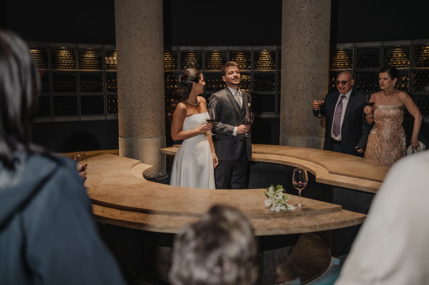 Bride and groom stand together at elegant wedding reception venue with ornate golden decor and curved bar.