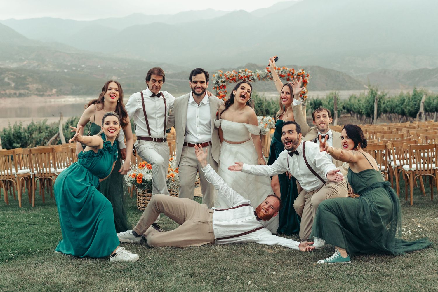 Group of wedding guests relaxing on grass at outdoor vineyard celebration with mountain views in background. fotografos de boda en mendoza