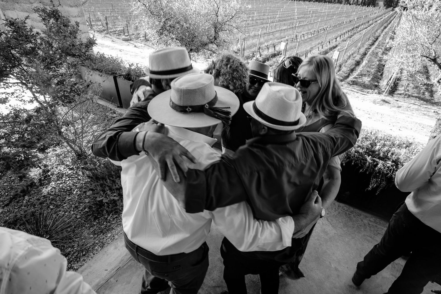 A group of people wearing hats sit together on a bench in a black and white photograph.